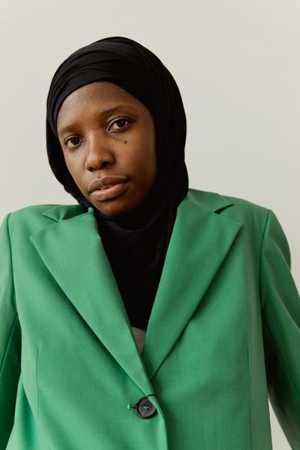 Stylish portrait of a woman wearing a headscarf and green jacket, exuding elegance.