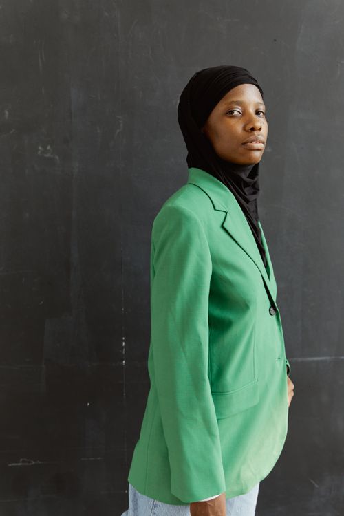 Free Confident Black woman wearing a green blazer and black hijab in a modern fashion pose. Stock Photo