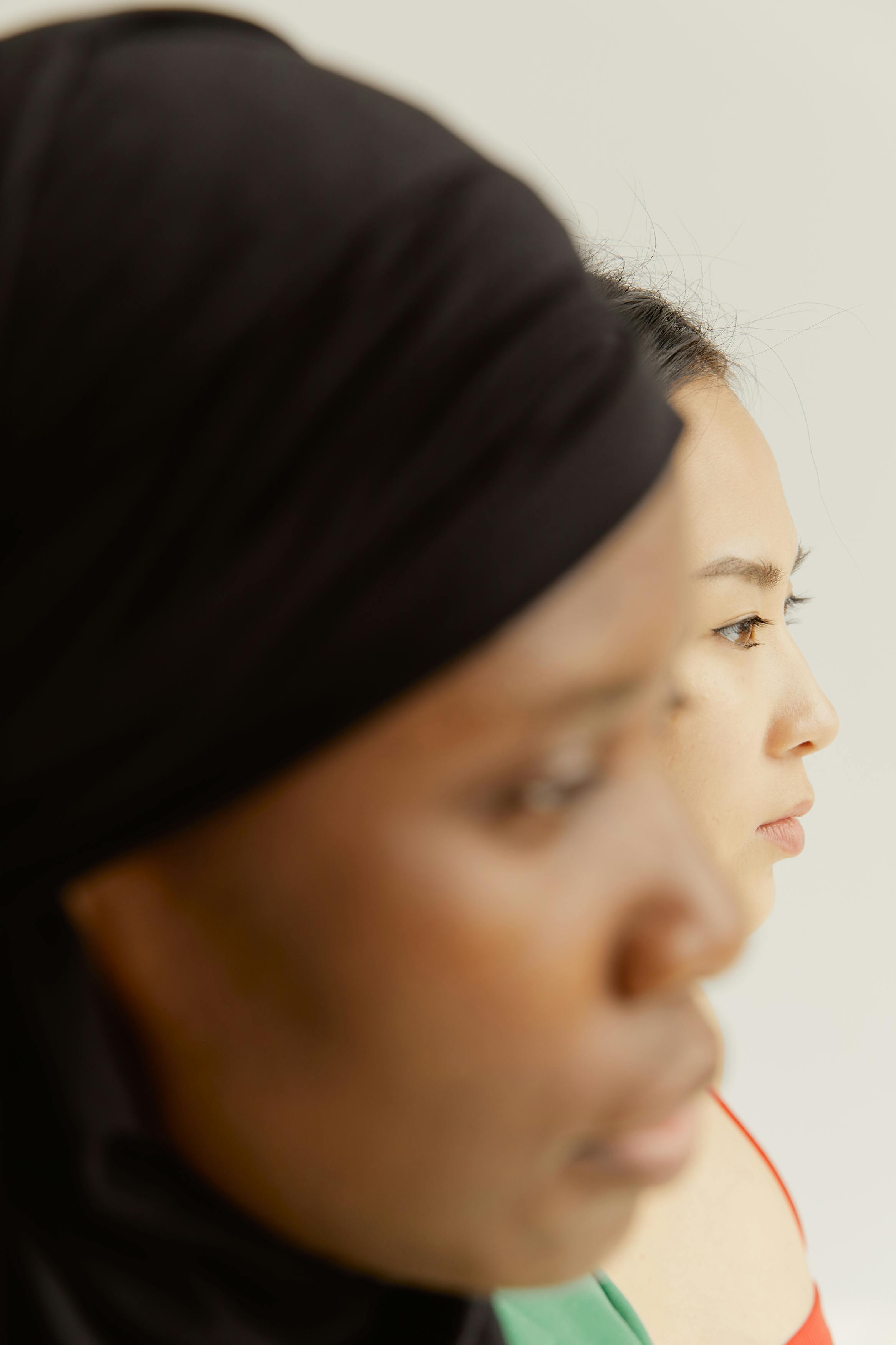 Artistic close-up portrait of two women from different ethnic backgrounds in profile, highlighting diversity and togetherness.