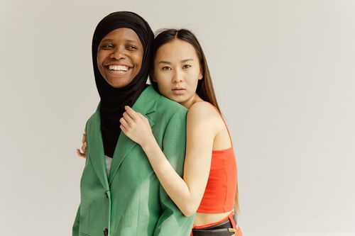 Free A joyful embrace between a smiling hijabi and an Asian woman symbolizing diversity and friendship. Stock Photo