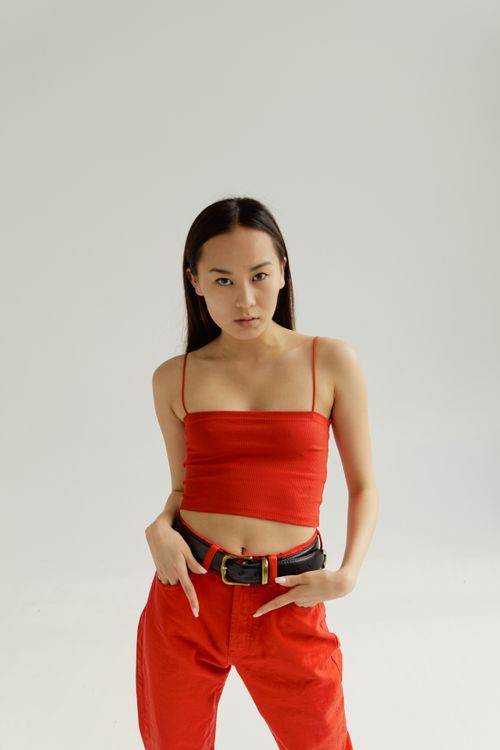 Free Elegant young woman in red outfit posing confidently against a minimalistic backdrop. Stock Photo