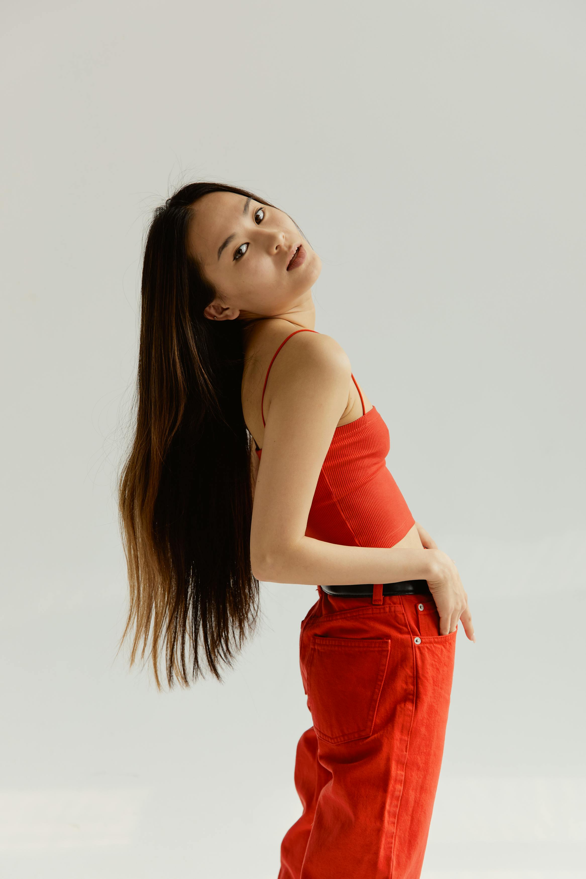 Elegant woman posing in red top and pants with minimalist background indoors.