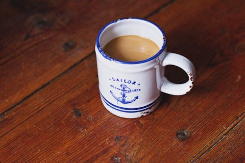 White and Blue Sailor Ceramic Coffee Mug on Brown Wooden Surface