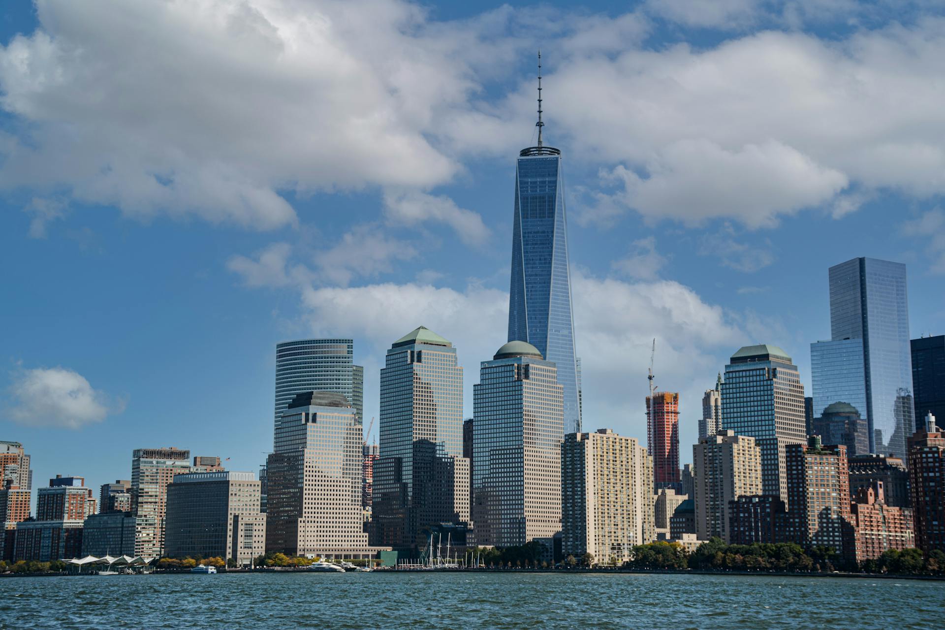 Stunning view of New York City skyline featuring the iconic One World Trade Center under a blue sky.