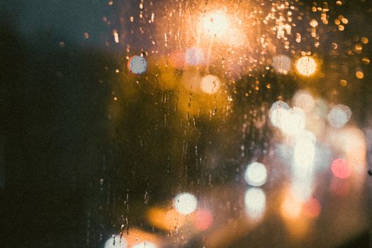 Bokeh lights seen through a rain-covered window, capturing the essence of a rainy night in a vibrant city.