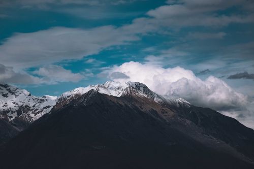 Free Picturesque view of high mountain slopes covered with snow in shadow under cloudy blue sky Stock Photo
