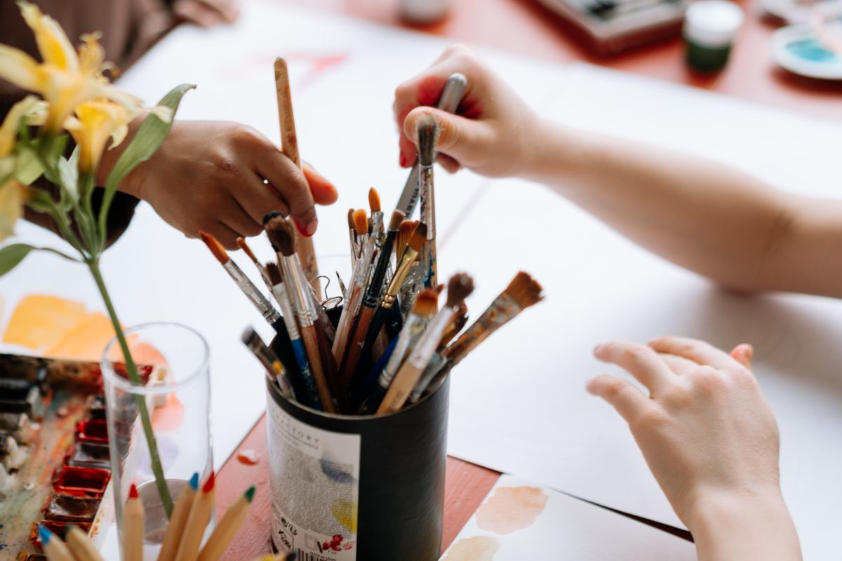Hands reaching for paintbrushes at a group art session