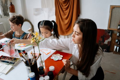 Free A woman in an art class instructing children in painting activities. Stock Photo