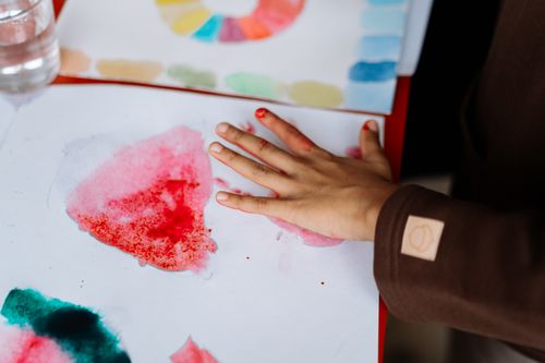 Free A child's hand engaged in watercolor painting, showcasing creativity and art expression. Stock Photo