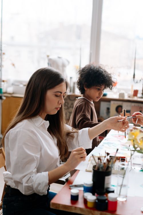 Free A woman and child engaging in a creative painting session at an art workshop. Stock Photo