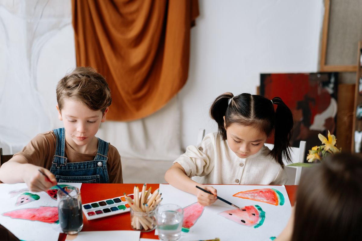 Two children having fun painting with watercolors at a table