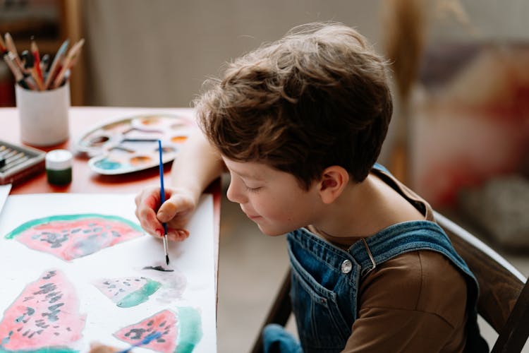 Young Boy Wearing Jumper Painting On A Paper