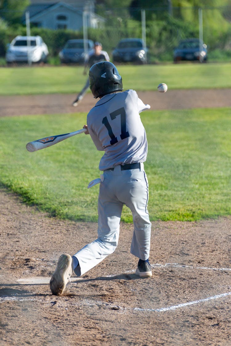 A Boy In White Jersey Holding Baseball Bat