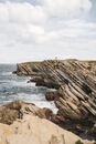 Brown Rock Formation on Sea Under White Clouds