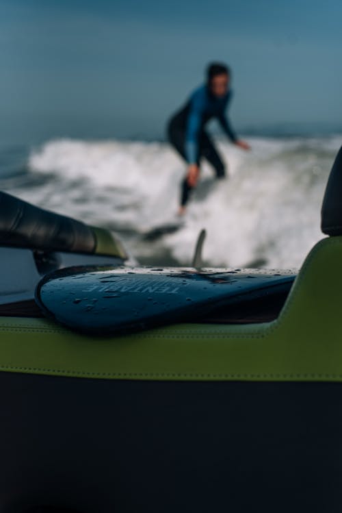 Free A Close-Up Shot of a Surfboard with a Surfer Riding a Wave on the Background Stock Photo