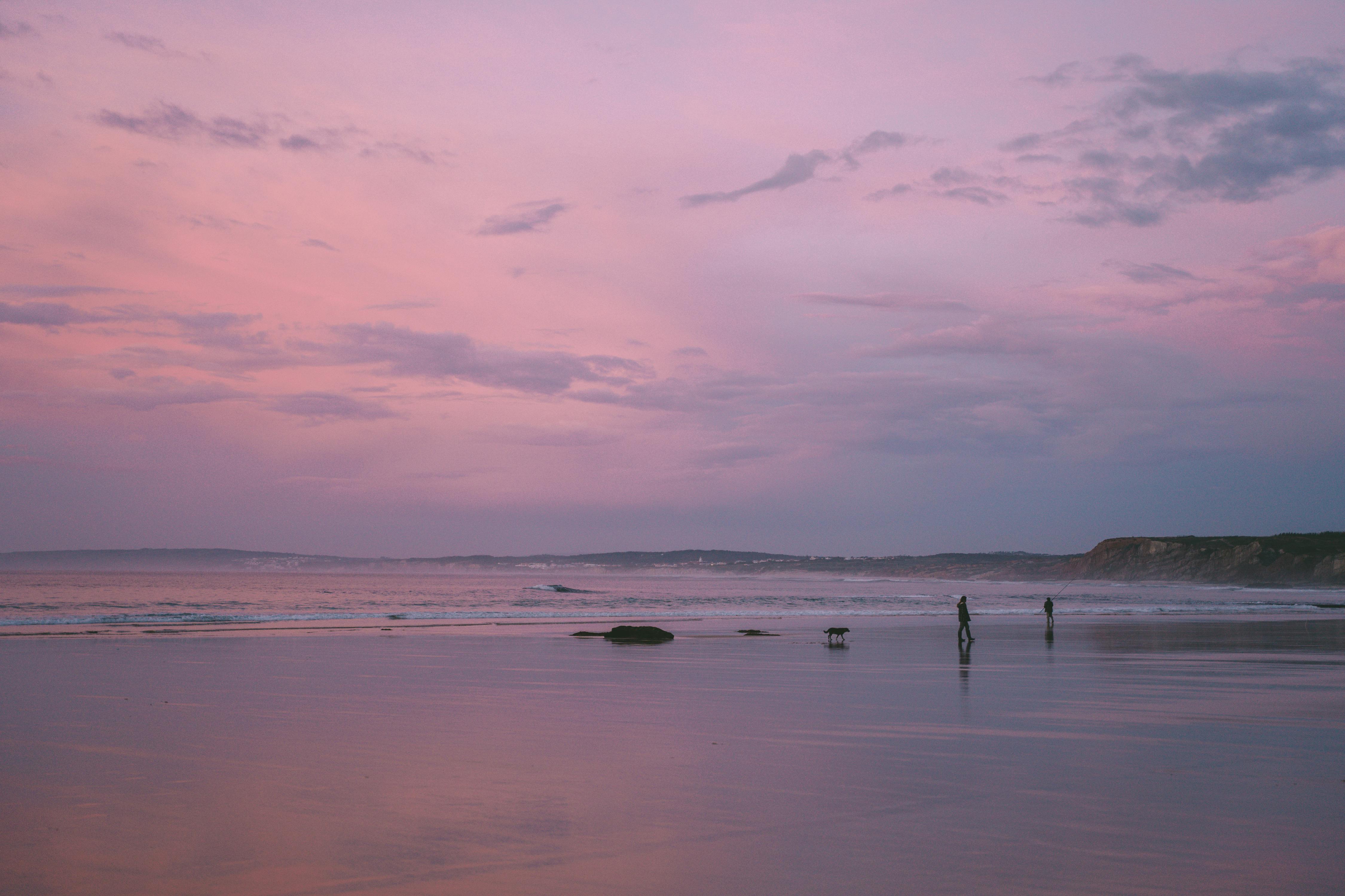 Serene sunrise beach scene with silhouettes against a pastel sky, perfect for relaxation themes.