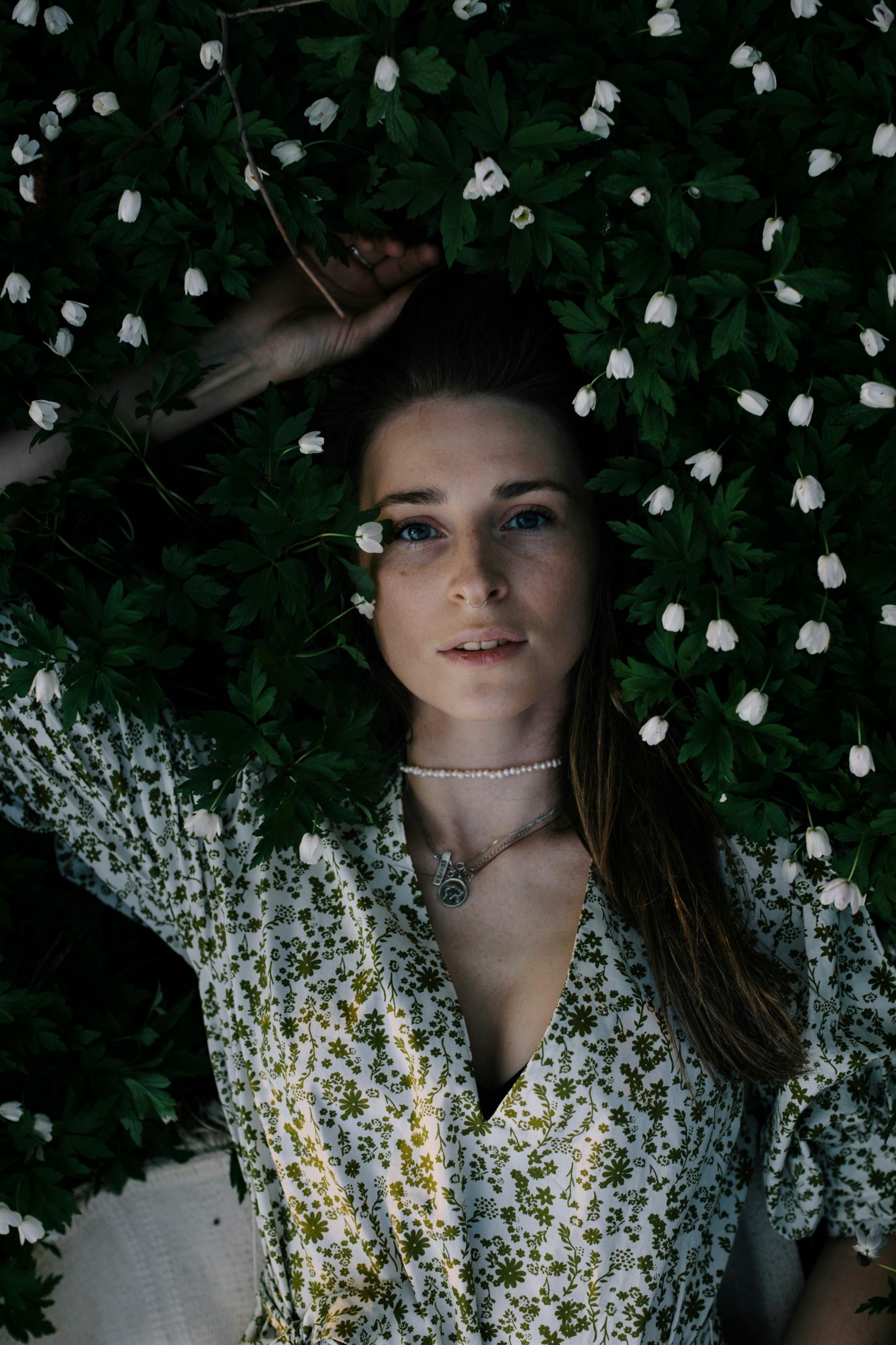 Stylish woman among small white flowers and green leaves  Free Stock Photo