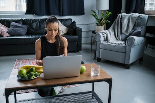 Woman focused on laptop work at home with fruits on the table, creating a healthy work environment.