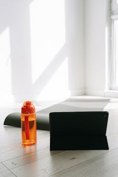 A bright and airy indoor space with a yoga mat, water bottle, and tablet ready for a home workout.