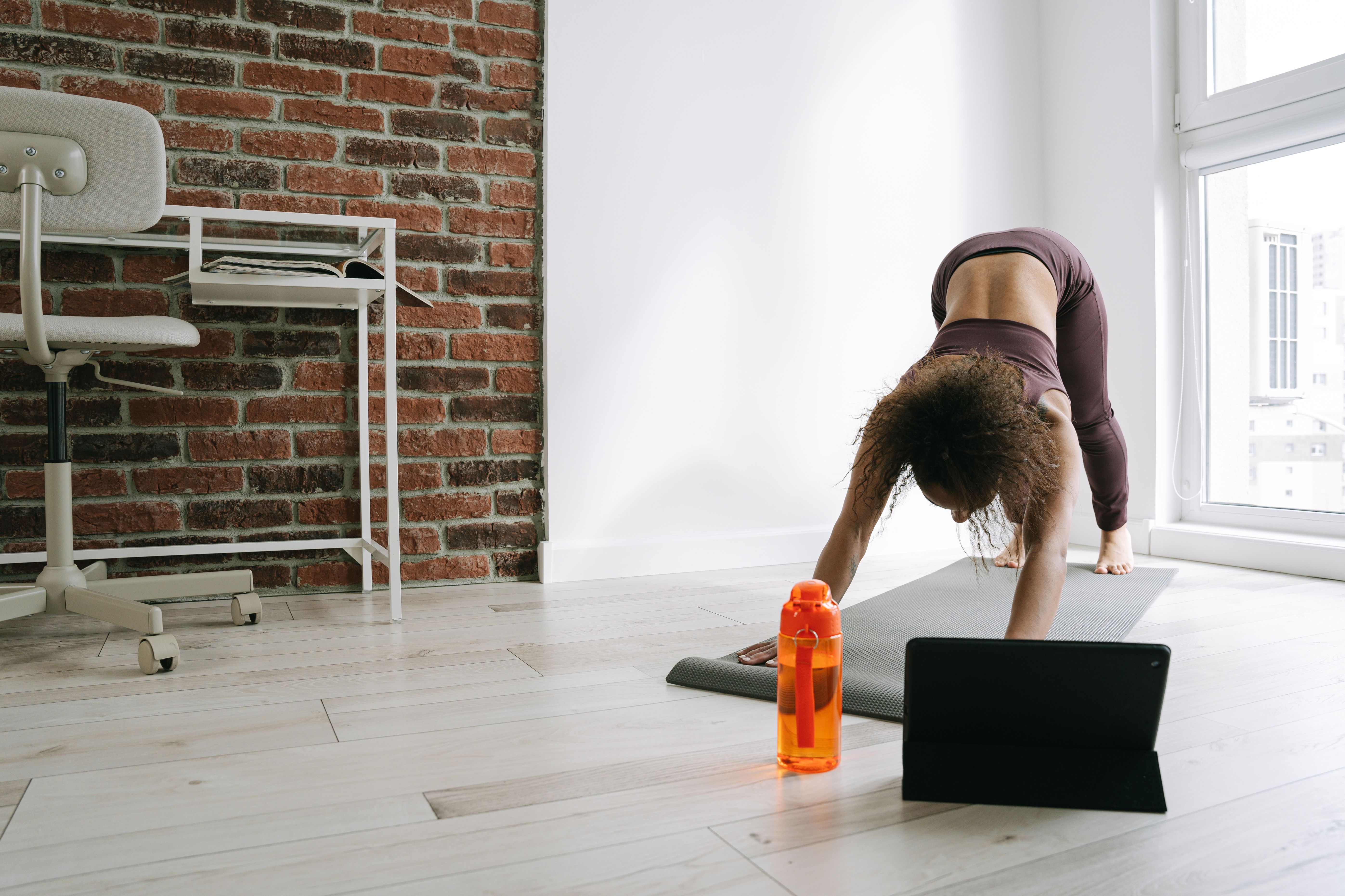 Woman practicing yoga at home with a tablet guide, emphasizing fitness and balance.