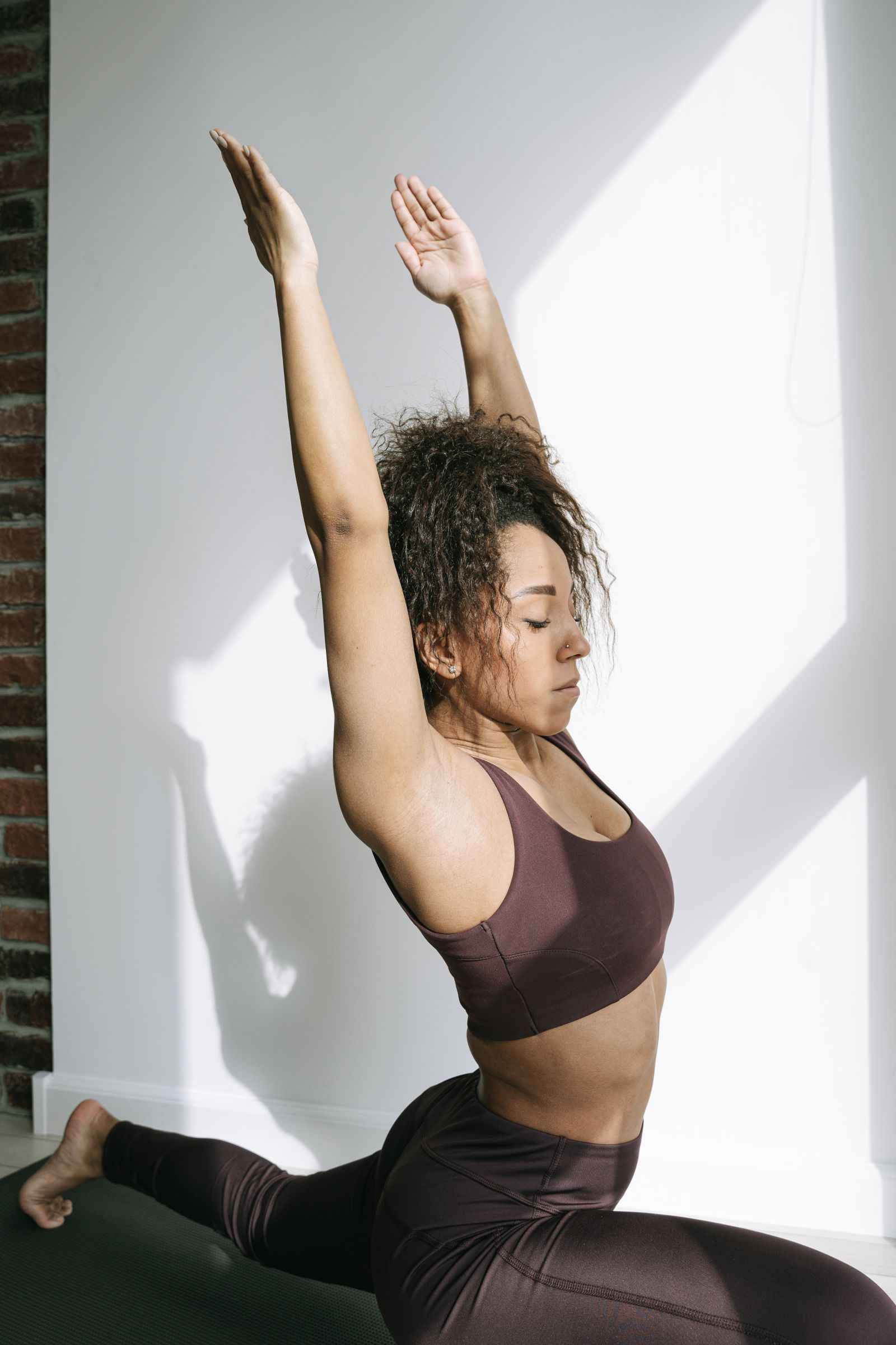 Mindful movement and raising arms Woman in a purple sports bra extending both arms in a yoga movement