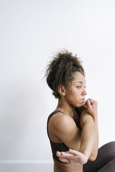 A focused African American woman doing yoga stretches at home, exemplifying a healthy lifestyle.