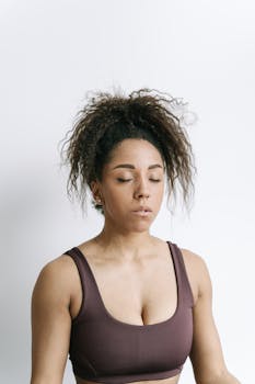 Meditating African American woman with closed eyes in stylish attire, embodying tranquility and focus.