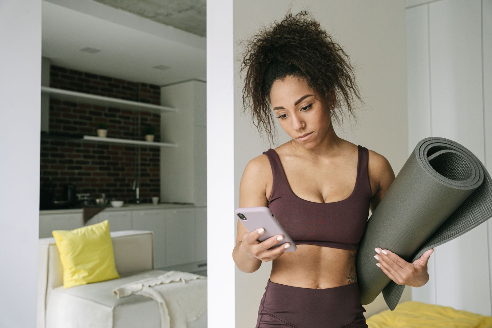 Person with a yoga mat checking a phone timer before a quick home yoga session