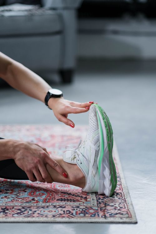 Free Close-up of a woman stretching her legs at home on a patterned carpet. Stock Photo