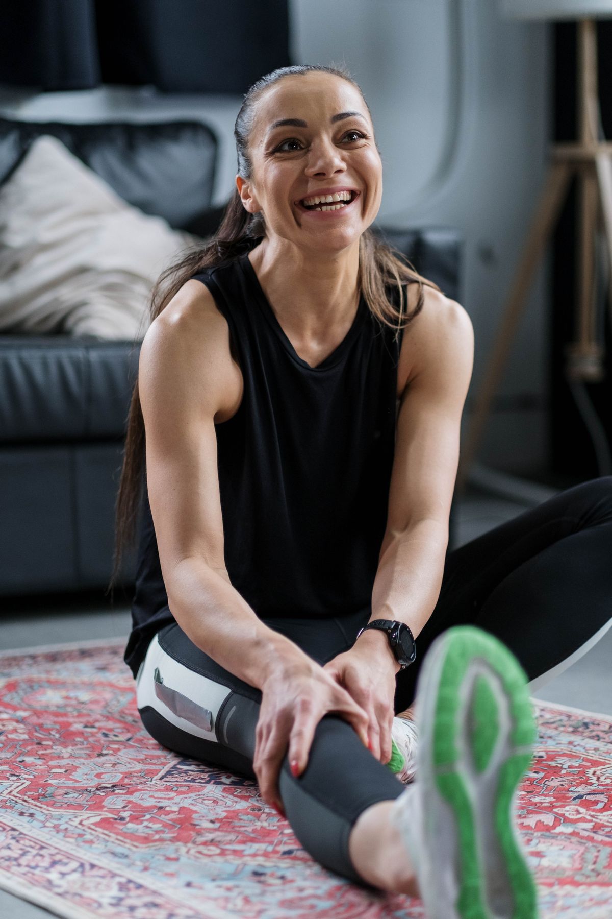 Smiling woman resting and stretching after a home workout, enjoying her training with no equipment