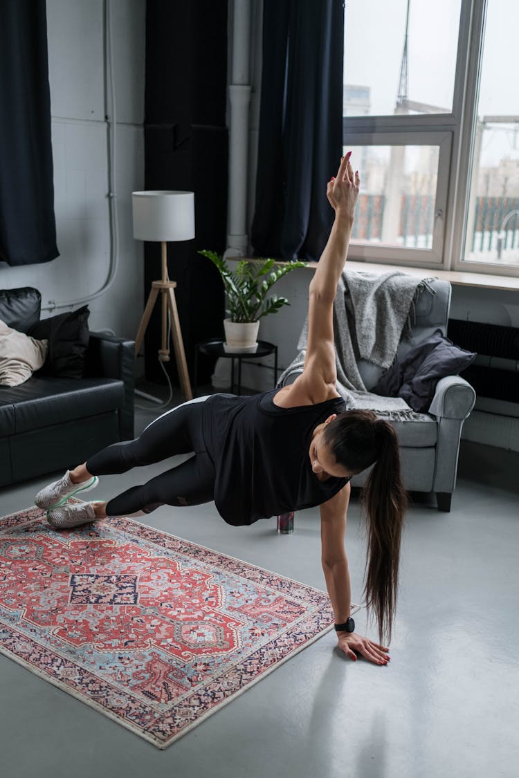 A Woman In Black Tank Top Doing A Side Plank