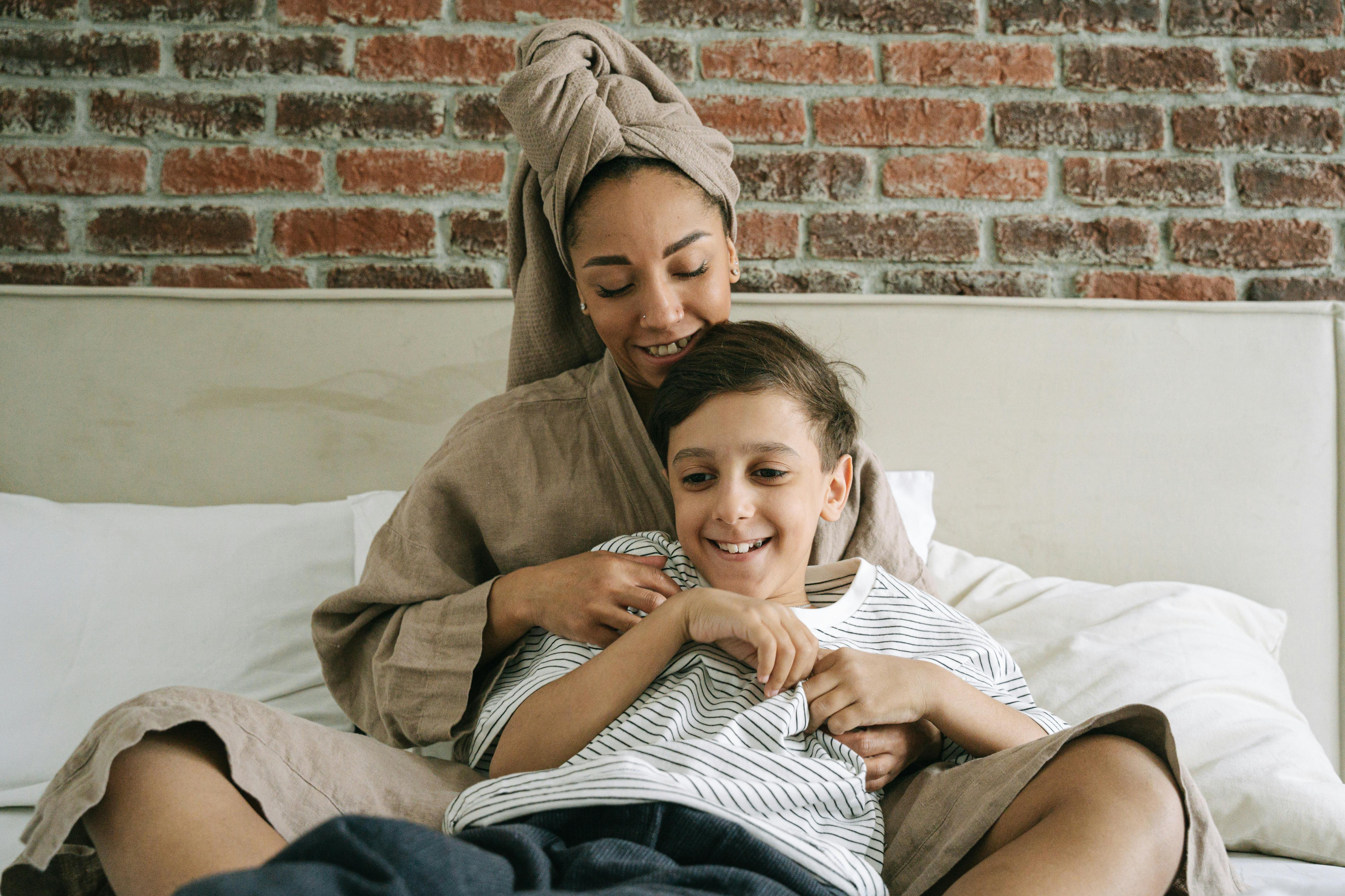 a boy leaning on her mother in bed