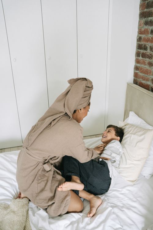 Free Enjoy a heartwarming moment of a mother and son sharing laughter and love on a cozy bed. Stock Photo