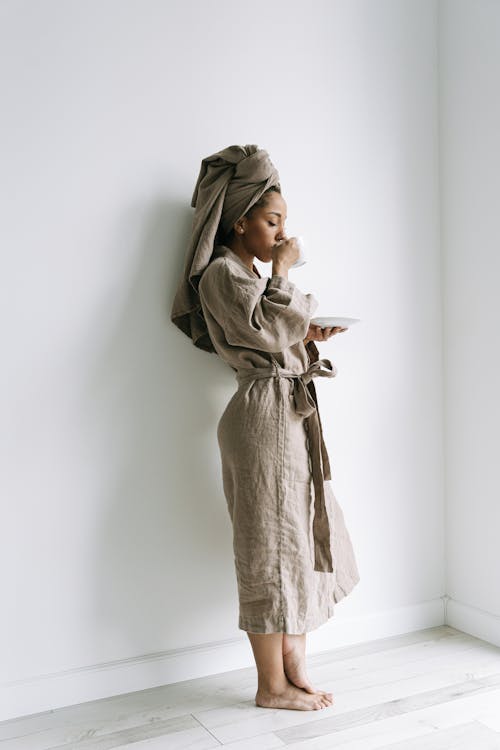 Woman in Gray Bathrobe Standing with Drink