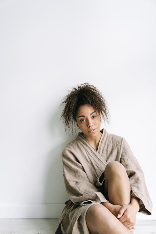 Woman Wearing a Robe Leaning on White Wall