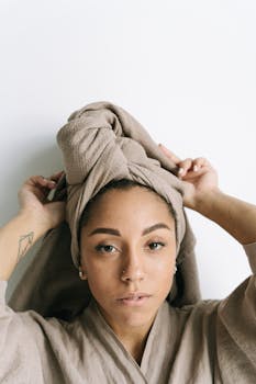 Elegant portrait of woman in bathrobe with towel turban, exuding calmness and style.