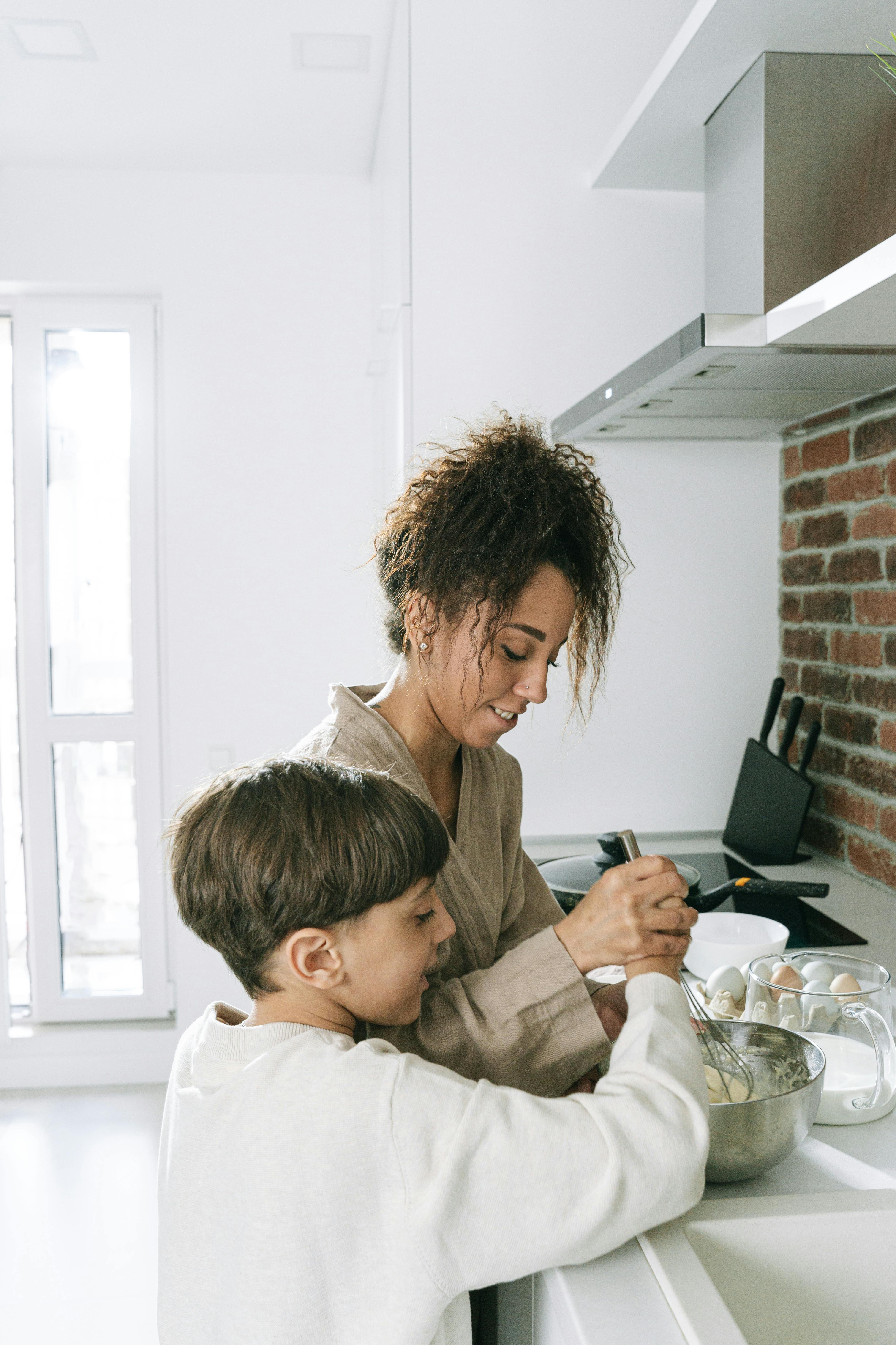 mother and son holding a whisk on stainless bowl