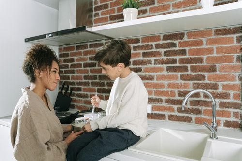 Free A mother and son enjoying quality time together while cooking in a modern kitchen. Stock Photo