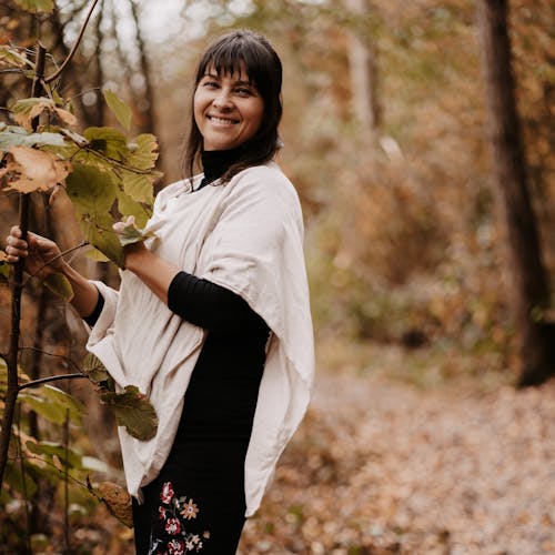 Smiling woman standing near plant in autumn forest