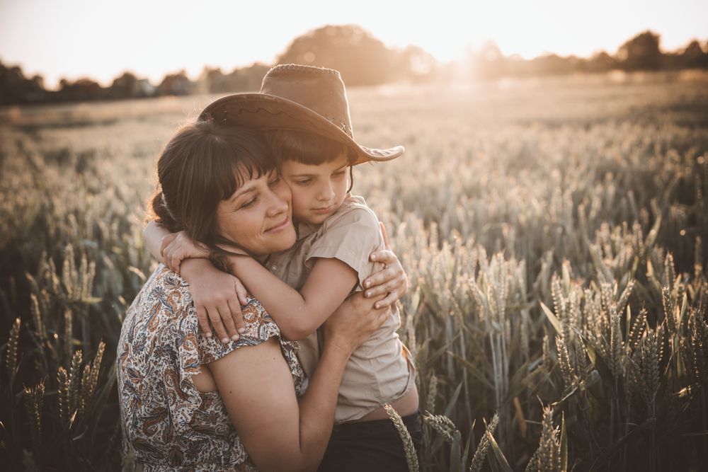 Campesino mexicano abrazando a su mamá en el campo al atardecer