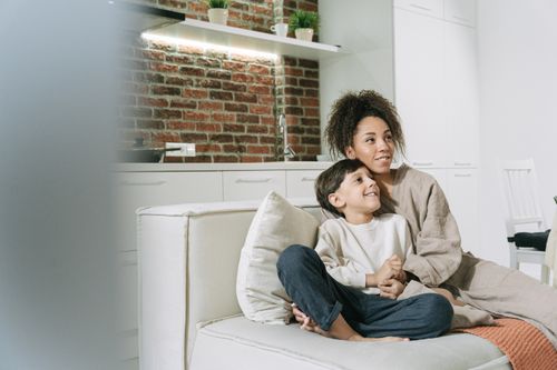 Free A loving mother and son enjoying quality time on a couch in a cozy living room setting. Stock Photo