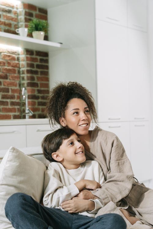 Free A joyful mother and son enjoying quality time together on a couch in a cozy home setting. Stock Photo