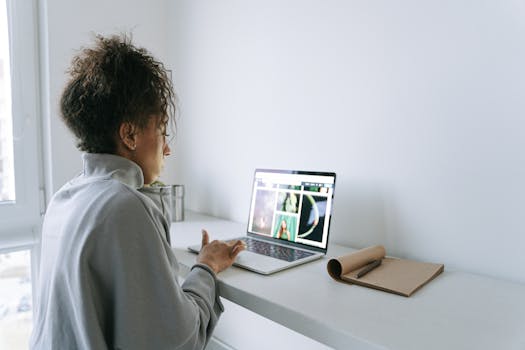 A woman engaged in remote work, typing on a laptop at a home office desk.