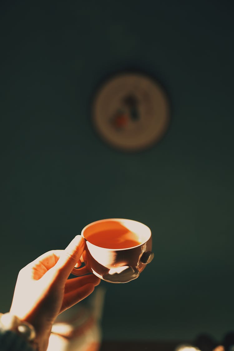 Person Reaching Out Hand With Cup Of Tea In Room