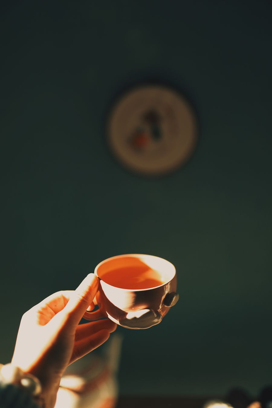 A hand wrapped around a warm cup of tea in a sunlit room