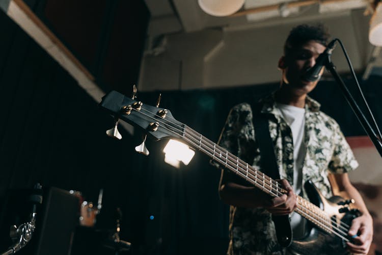 
A Man Playing A Bass Guitar While Singing