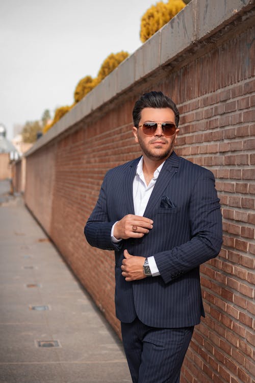 A Stylish Businessman Standing Near a Brick Wall