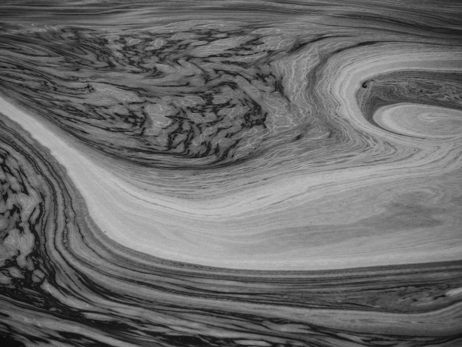 Intricate black and white abstract patterns resembling swirling water or liquid merging on a surface.