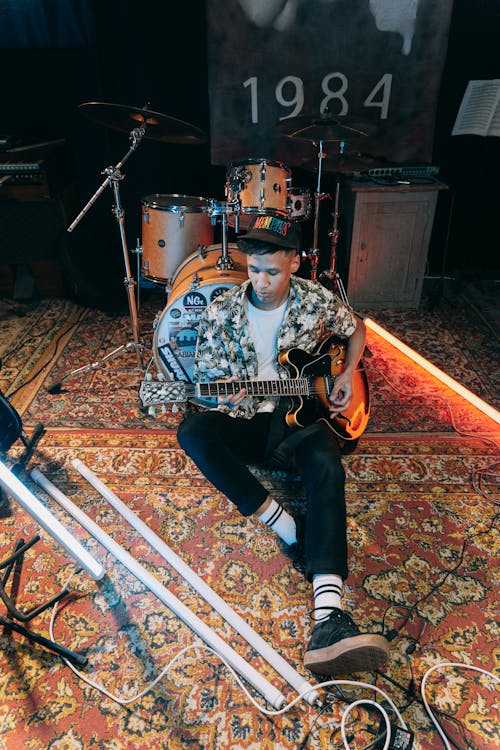 A Musician Playing the Electric Guitar while Sitting on the Floor