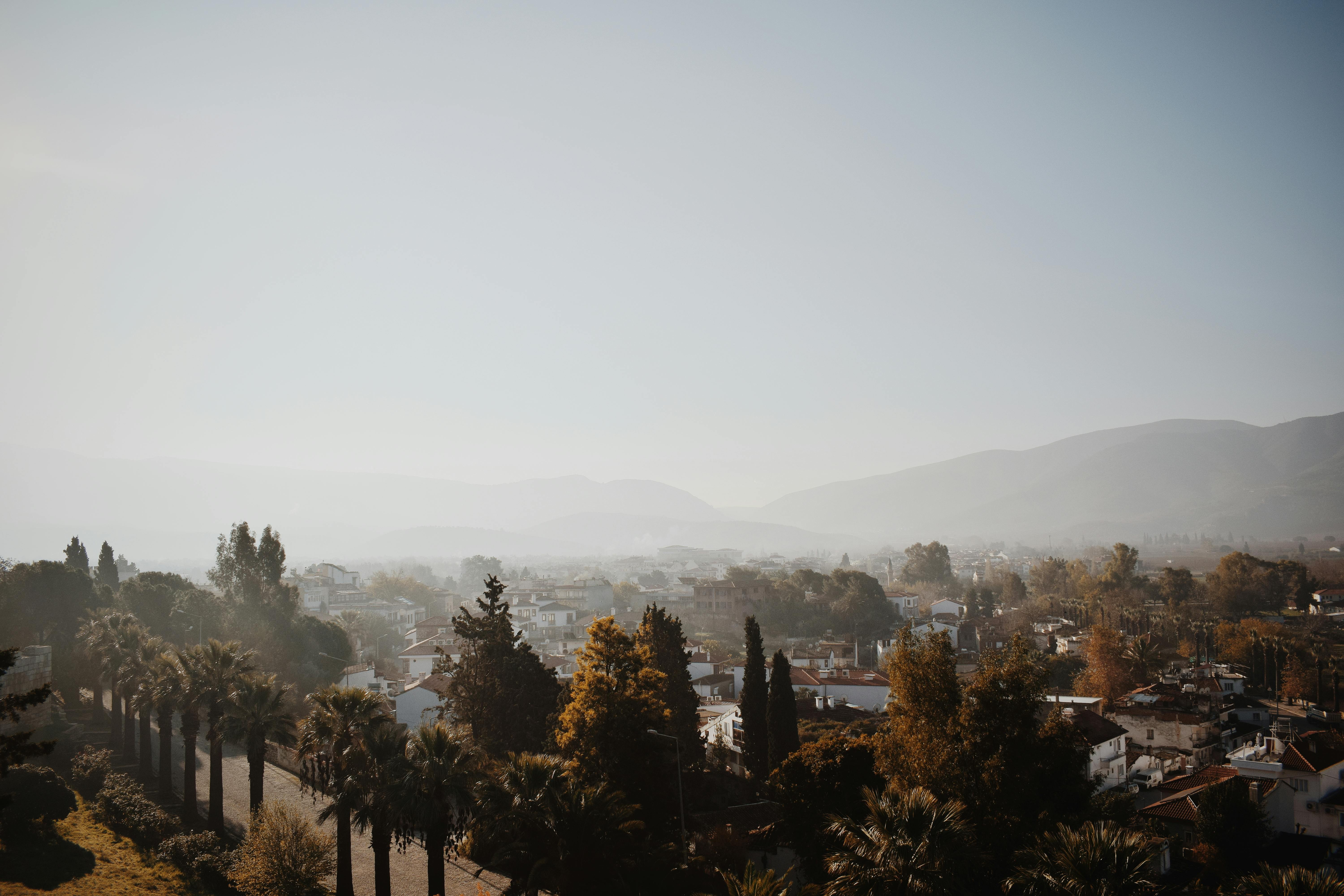 A serene aerial view of a cityscape in Turkey surrounded by misty hills and lush greenery.